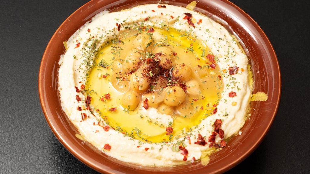 Hummus · Mashed chickpeas blended with tahini, olive oil, lemon juice, salt and garlic. Served with a side of pita bread.