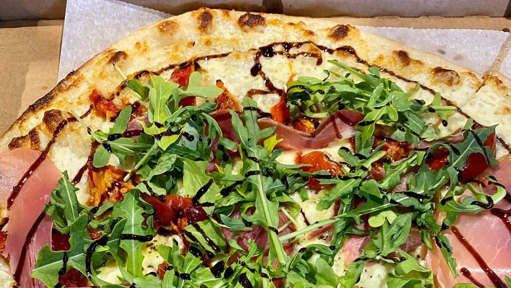 Prosciutto & Arugula · White pizza (no red sauce) with mozzarella, roasted tomatoes and prosciutto. Arugula and balsamic glaze are added after the oven.