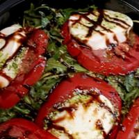 Caprese Salad · Sliced tomatoes, house-made Mozzarella, fresh basil pesto (no nuts), over arugula finished w...