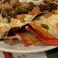 Loaded Nachos · Our tri-colored nacho chips are layered with house made queso and cheddar jack cheese.  Topp...