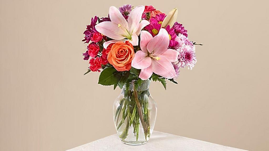 Light Of My Life Bouquet · The Light of My Life Bouquet blossoms with brilliant color and a sweet sophistication to create the perfect impression! Pink Lilies make the eyes dance across the unique design of this flower bouquet, surrounded by the blushing colors of orange roses, lavender cushion poms, hot pink carnations, and lush greens. Vase included. Please Note: The bouquet pictured reflects our original design for this product. While we always try to follow the color palette, we may replace stems to deliver the freshest bouquet possible. Item # C5375S