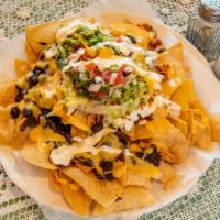 Nachos · Crispy corn tortilla chips topped with black beans, lettuce, tomato, melted cheese, sour cre...