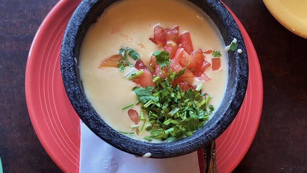 Queso Dip · A blend of creamy cheeses melted dip and roasted green chilies, garnished with cilantro and tomatoes