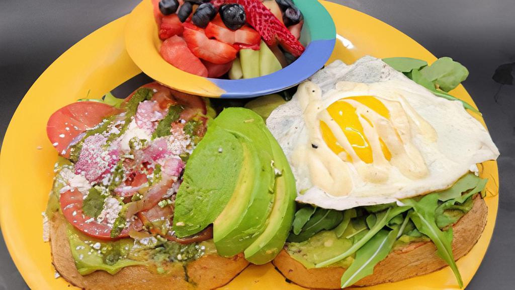 Sally'S Avocado Toast · Our whole wheat toast loaded with avocado: One side served with arugula, a sunny side up egg & everything bagel aioli. The other with sliced tomato, cotija cheese, Chimichurri & pickled onions. Served with fresh fruit salad.
