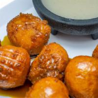 Nuegados Con Chilate · Deep fried cassava bites served with real cane syrup and purple corn porridge.