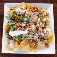 Nachos Tejanos · Grilled chicken, steak & shrimp over crispy tortilla, lettuce, pico de gallo, jalapenos, a s...