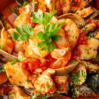 Cacciucco · Shrimp, clams, mussels, scallops, and salmon in a broth saffron tomato sauce served over spa...
