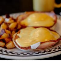Famous Eggs Benedict · 2 poached eggs, Canadian style bacon and tomato on top of a toasted Portuguese muffin and to...
