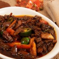 #22. Rohobot Yawaze Tibs · Strip of beef sauteed in seasoned butter, hot peppers, onions, and awaze paste; served on re...