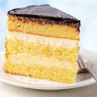 Boston Crème Cake Slice · Three layers of moist, velvety gold cake filled with rich vanilla bean pastry cream and fres...