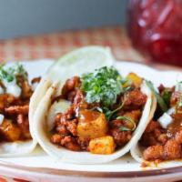 Al Pastor Tacos · Pork shoulder and pineapple. Garnished with white onion, cilantro, and lime. Three per order.