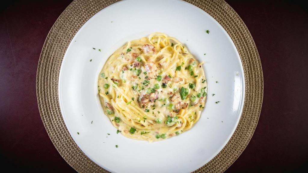 Linguine Carbonara · Linguine pasta in a traditional carbonara sauce. Made with pancetta, onions, green peas, egg yolk and a touch of cream. Finished with romano cheese and black pepper.