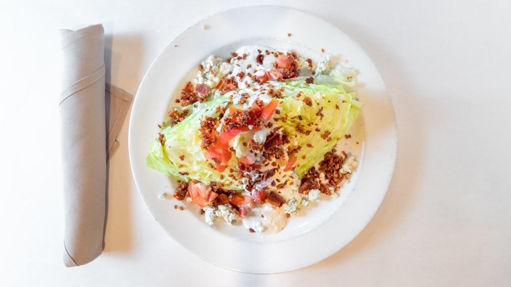 Iceberg Wedge Salad · Gluten conscious. Crisp wedge of fresh iceberg topped with crumbled blue cheese, bacon, diced tomatoes, with blue cheese dressing.
