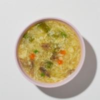 Egg Drop Soup · Wispy beaten eggs in a flavorful chicken broth with peas and carrots.