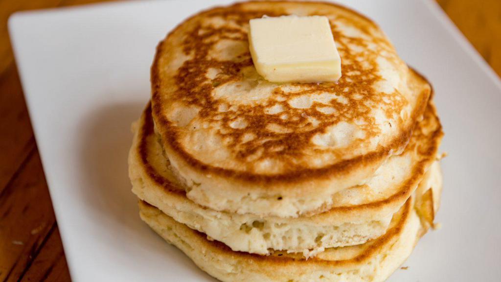 Buttermilk Pancakes · stack of 3 fluffy buttermilk pancakes topped with butter, syrup and powdered sugar