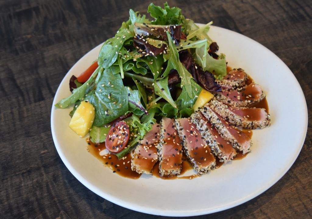 Ahi Tuna* · seared rare with black pepper & toasted sesame seeds and drizzled with a sweet soy glaze, over mixed greens, arugula, seaweed salad, cucumbers, scallions, pickled ginger and diced mango in an orange-sesame vinaigrette. 

*This item may be cooked to order. Consuming raw or undercooked meat, seafood, or eggs may increase your risk of foodborne illness.