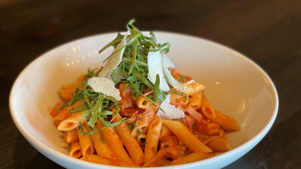 Penne Alla Vodka · simply delicious in a light tomato cream sauce with prosciutto, basil, arugula, roasted red peppers and shaved romano cheese.