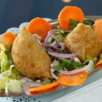 Vegetable Samosa · Vegan. Two pieces. Deep-fried crispy lightly spiced turnovers stuffed with potato and peas.