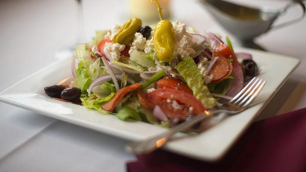 Greek Salad · Mixed greens, red onions, green bell peppers, roma tomatoes, & pepperoni tossed in our homemade italian dressing & garnished with feta chaase, kalamata  olives, & pepperocinnis.