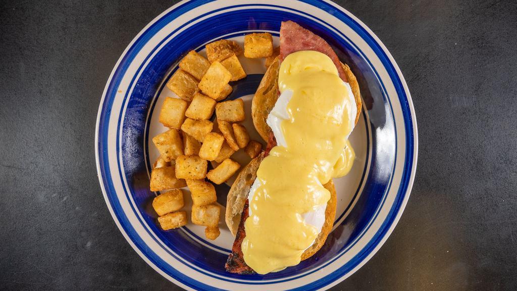 Eggs Benedict · Two poached eggs served over English muffin with ham and topped with hollandaise sauce served with home fries.