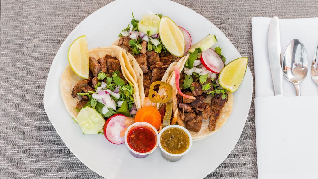 Steak Tacos · Three tacos served with corn tortilla, onions cilantro and hot sauce on the side.