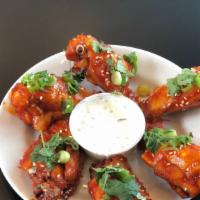 Korean Chicken Wings · Tossed with sesame seeds, scallions, and cilantro. Served with a lemon blue cheese dipping s...