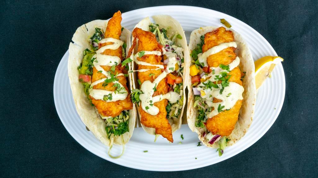 Fish Tacos · Baked or Fried Haddock. Served in fresh flour tortillas with seasonal slaw, avocado spread, mango salsa, and drizzled with an avocado/poblano aioli