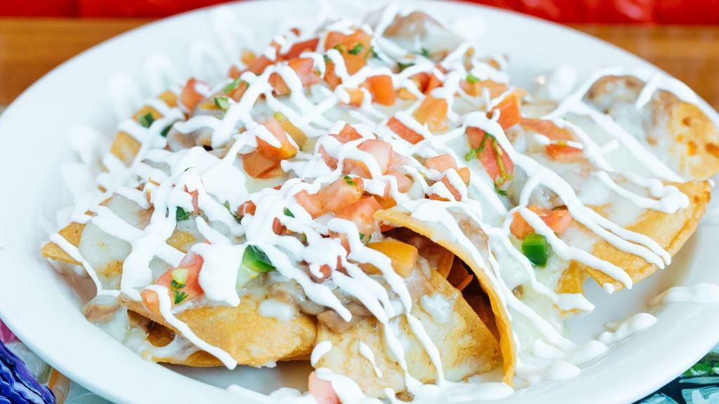 Nachos Grande · Home-made crispy corn tortilla chips pilled with beans and melted cheese, topped with sour cream, pico de gallo, and guacamole.