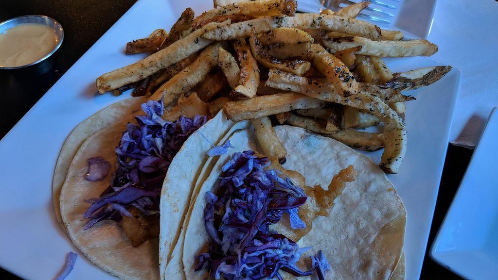 New England Fish Tacos · Battered and fried haddock, house slaw, drizzled with Caribbean tartar sauce. Served atop a grilled corn tortilla with hand cut fries.