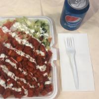 Chicken Over Rice · With salad in the side white sauce hot sauce on top and a can soda