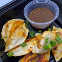 Pork And Scallion Dumplings · 6 pan-seared pork and scallion filled dumplings topped with chili crunch, with a side of Sze...
