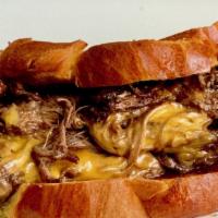 Hand-Cut Beef Brisket · Caramelized Onions and Cheese Fondue, served on a soft bun.