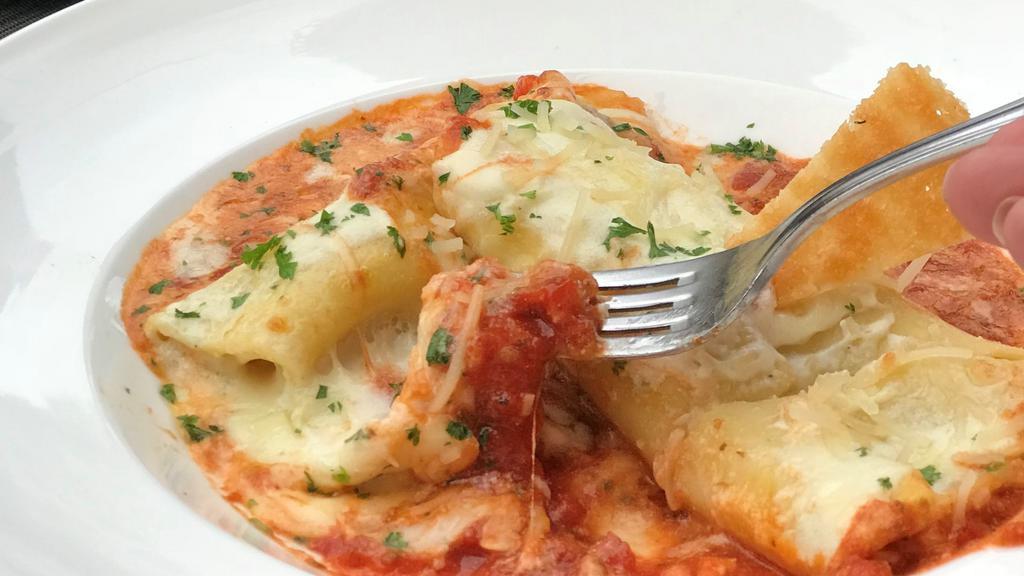 Manicotti · Hand-rolled manicotti pasta stuffed and baked with mini-meatballs, ricotta and Parmesan cheeses, bechamel tomato sauce and fontina cheese.
