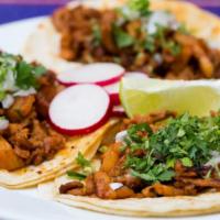 Tacos Al Pastor · Pork meat marinated in guajillo sauce and pineapple tacos served with cilantro and diced oni...
