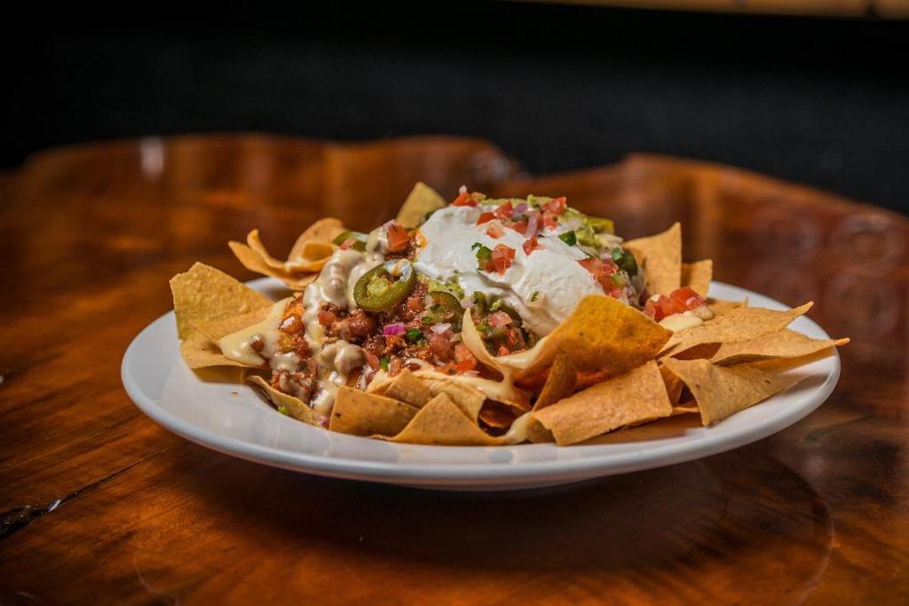 Traditional Nachos · Freshly fried corn tortilla chips topped with your choice of main ingredient, beans, sour cream, guacamole, of course melted cheese, jalapenos, and pico de gallo.