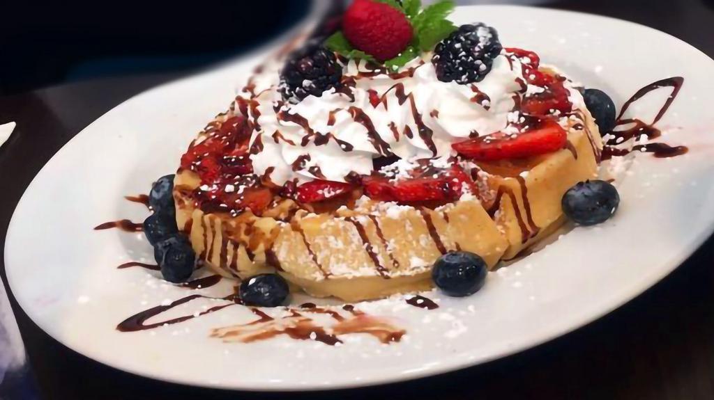 Triple Berry Waffle · One large, thick waffle with delicious homemade custard, topped with whipped cream, strawberries, blackberries, blueberries and chocolate drizzle.