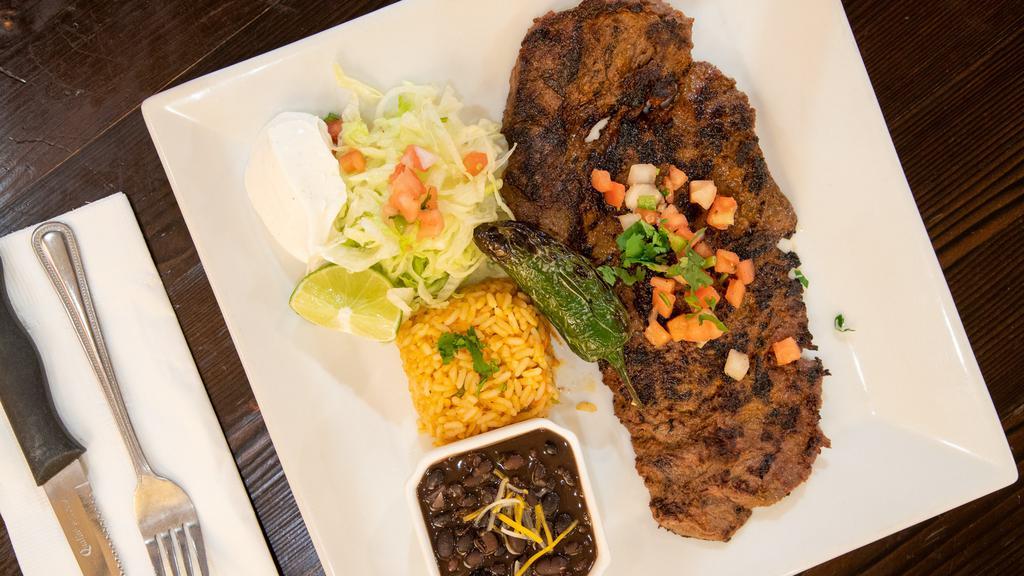 Carne Asada · grilled marinated skirt steak finished in garlic sauce, served with white rice, black beans, pico de gallo & guacamole