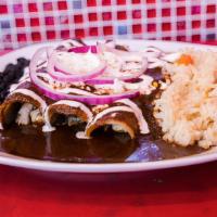 Enchiladas De Mole · Corn tortillas with chicken in a traditional Mexican mole sauce topped with fresh Mexican ch...