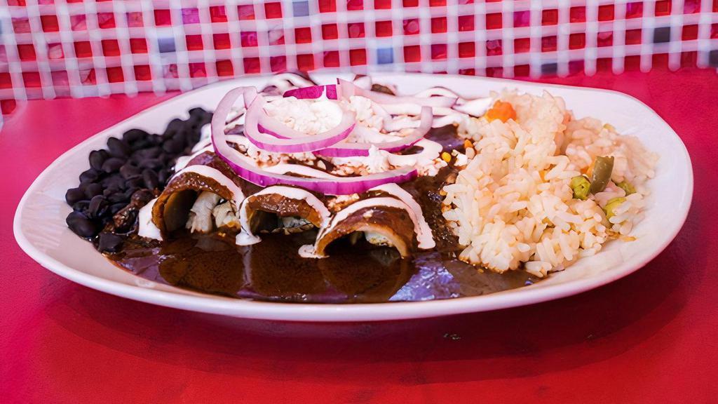 Enchiladas De Mole · Corn tortillas with chicken in a traditional Mexican mole sauce topped with fresh Mexican cheese, onions, and crema (sour cream).