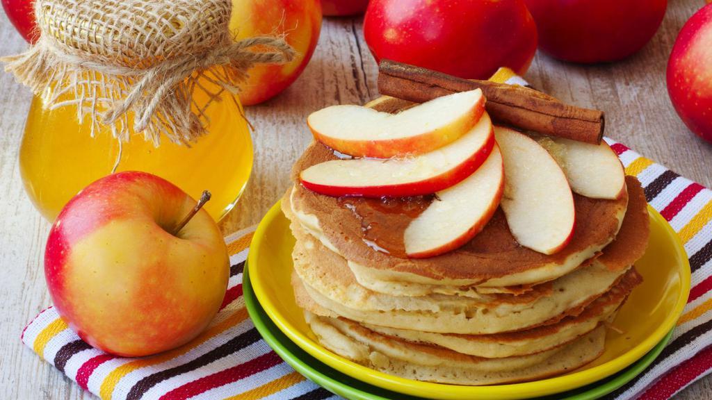 Apple Cinnamon Pancakes · Cinnamon flavored pancakes with finely chopped apples on top, served with butter, whipped cream and powdered sugar.