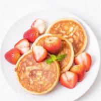 Strawberry Pancakes · Buttermilk pancakes topped with fresh strawberries, served with butter, whipped cream and po...