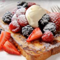 Berry French Toast · Three slices of thick, egg-washed challah bread topped with fresh blueberries and strawberri...