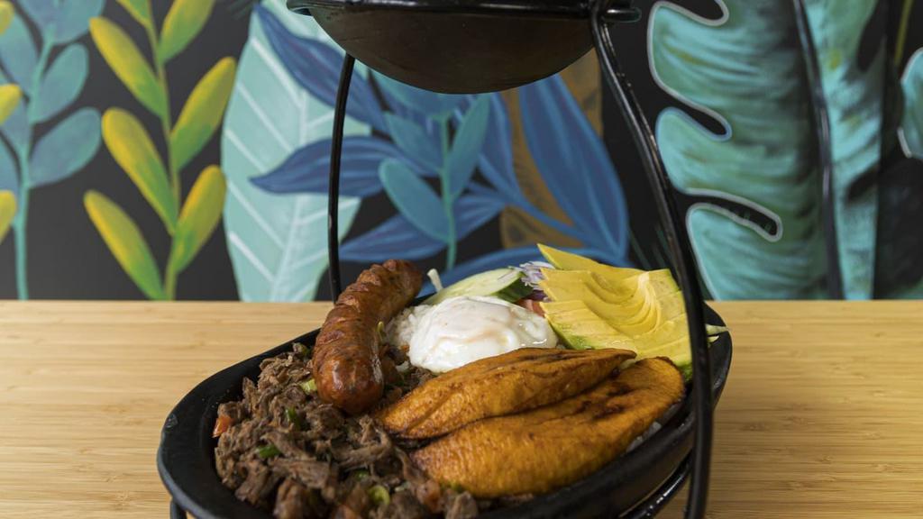 Súper Bandeja · Shredded Beef with tomatoes and onions, chicharrón, chorizo, avocado, sweet plantains, fried egg, rice, beans and salad