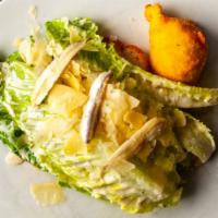 Caesar Salad · Whole leaves of baby Romaine tossed in a white truffle infused dressing. Served with white a...