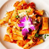 Rigatoni Bolognese · Homemade rigatoni pasta tossed in a slow cooked sauce of tomatoes, and red wine. Topped with...