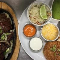 Kalbi Fajitas · Grilled beef short rib strips served in skillet with sliced bell peppers and onions. Served ...