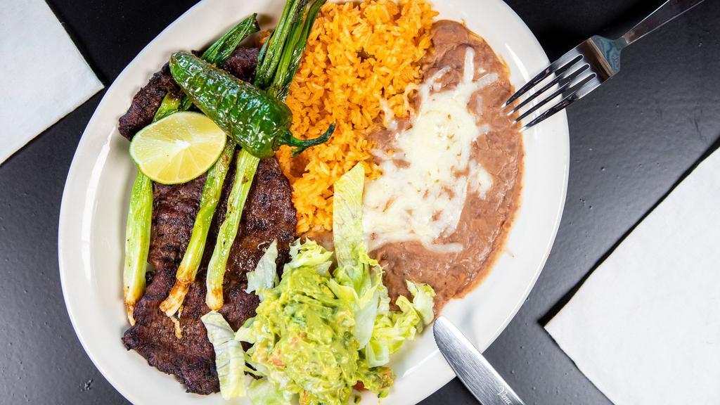 Carne Asada · Charbroiled skirt steak served with rice, beans and guacamole. Garnished with grilled green onions, lettuce and tomato.