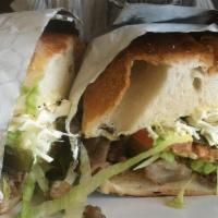 Tortas De Carnitas · Hot sandwich with pork, refried beans, cheese, hot peppers, onions, lettuce, tomatoes and av...