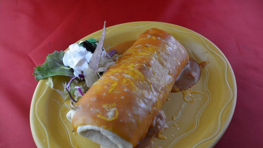 Super Burrito · Not spicy. A soft flour burrito filled with beef and beans with cheese. Topped with rancera sauce and garnished with sour cream.