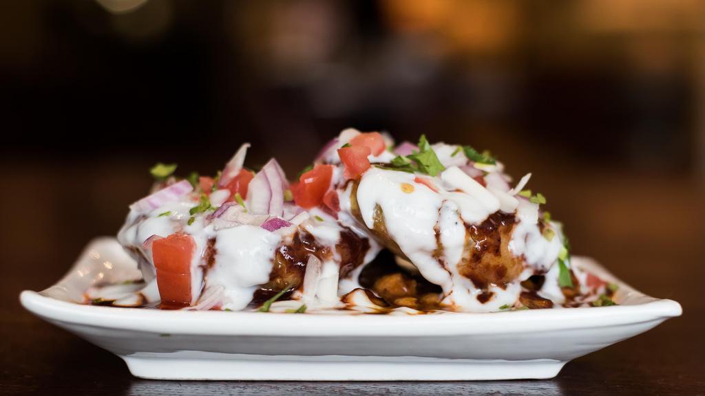 Aloo Tikki Chaat · Panfried potato cakes on a bed of chickpeas, sweet yogurt and sauces.